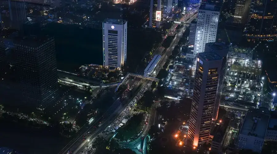 Aerial view of Jakarta cityscape at night featuring busy streets and illuminated skyscrapers.
