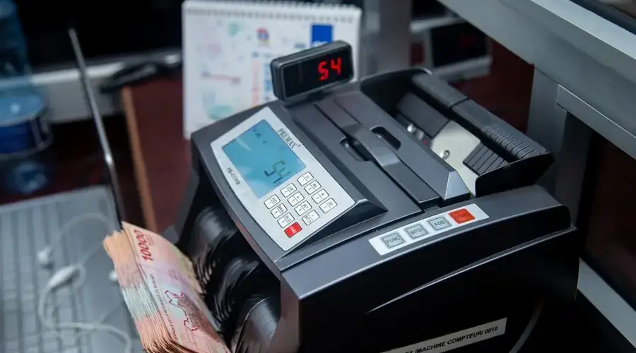 Automatic money counter in a modern office counting banknotes efficiently.