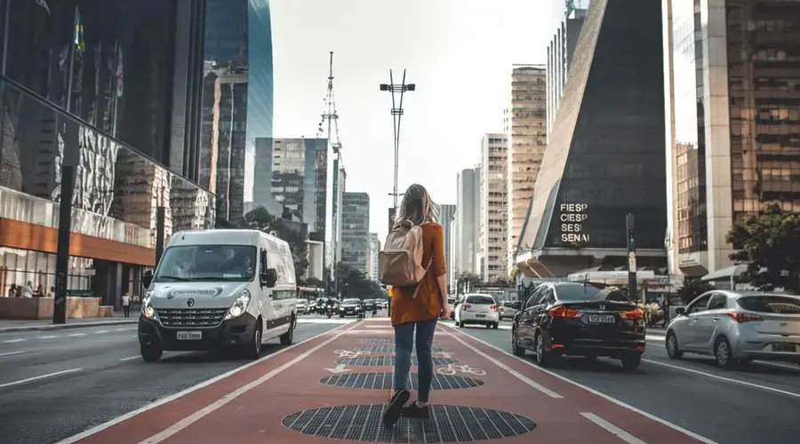 Woman walking in urban street surrounded by skyscrapers and modern architecture.