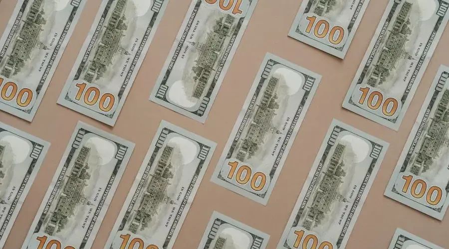 Patterned display of 100 US dollar bills, showcasing wealth and finance themes.
