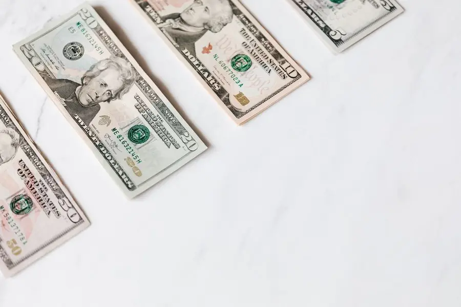 From above of US dollar banknotes in different denominations placed in row on white surface