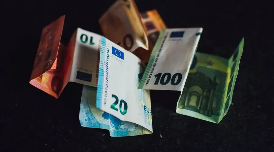 Assorted Euro banknotes in denominations of 10, 20, and 100 on a dark surface, highlighting European currency.