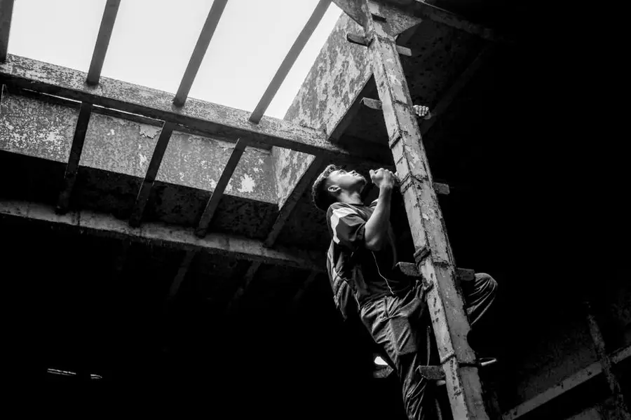 A young man climbs a rusty ladder inside an abandoned shipwreck in Bangladesh.