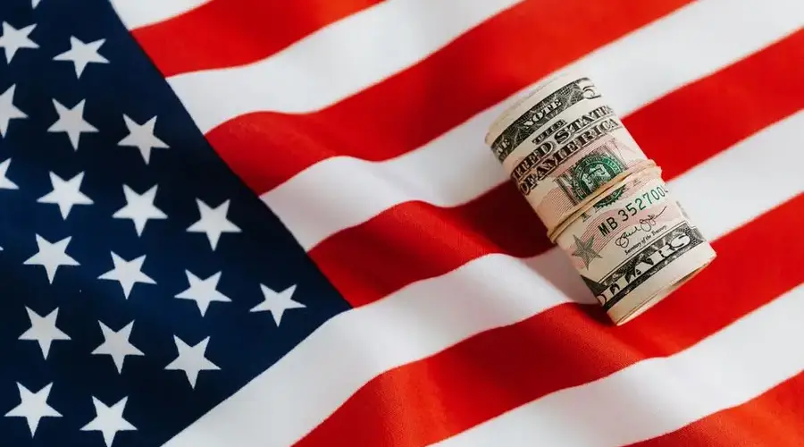 From above of United States currency folded in roll placed on USA flag illustrating concept of business profit and wealth