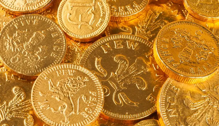 A close-up of gold-colored British pound and pence coins, showcasing intricate details.