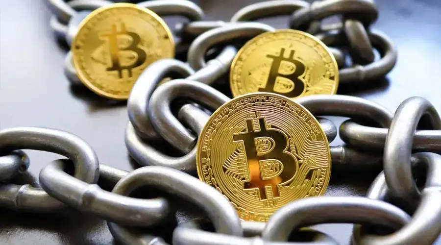 Close-up of Bitcoin coins entwined in metallic chains showcasing cryptocurrency security.