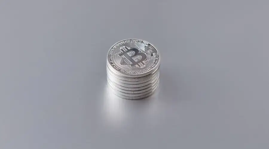 Close-up of silver Bitcoin coins stacked on a gray surface, showcasing cryptocurrency technology.