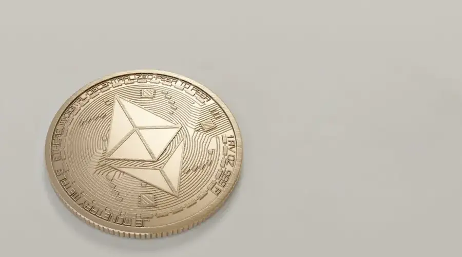 A golden Ethereum coin placed on a neutral light background, symbolizing digital currency.