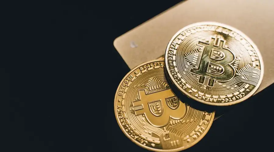 Close-up image of two gold bitcoin coins on a dark background, symbolizing cryptocurrency.