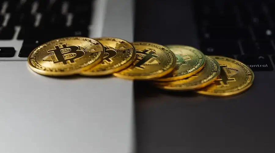 A stack of gold bitcoin coins placed on a laptop keyboard, symbolizing digital currency and finance.