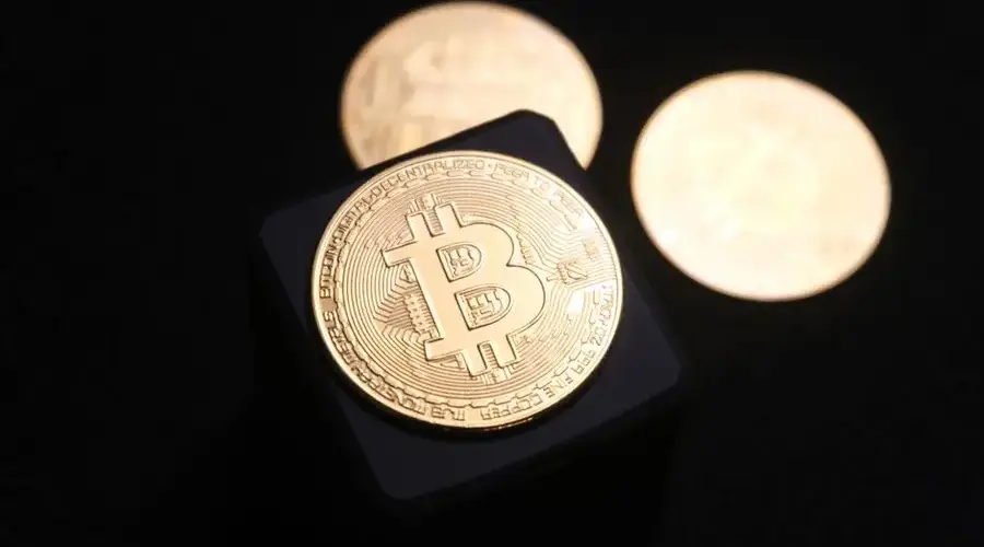 Close-up of golden Bitcoin coins on a sleek black background, emphasizing cryptocurrency themes.