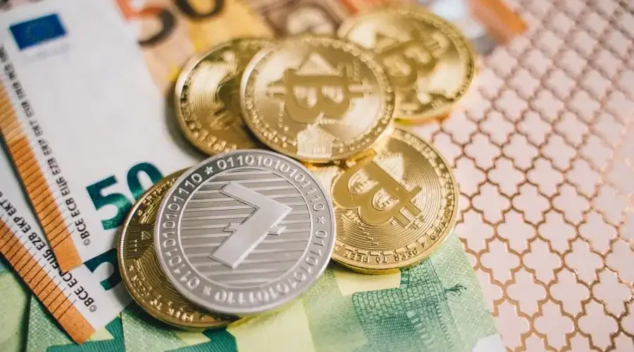 Close-up of digital cryptocurrency coins and Euro banknotes, representing modern finance.