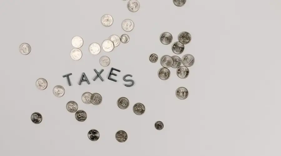 A visually striking flatlay of coins with 'Taxes' text on a white surface, ideal for financial concepts.