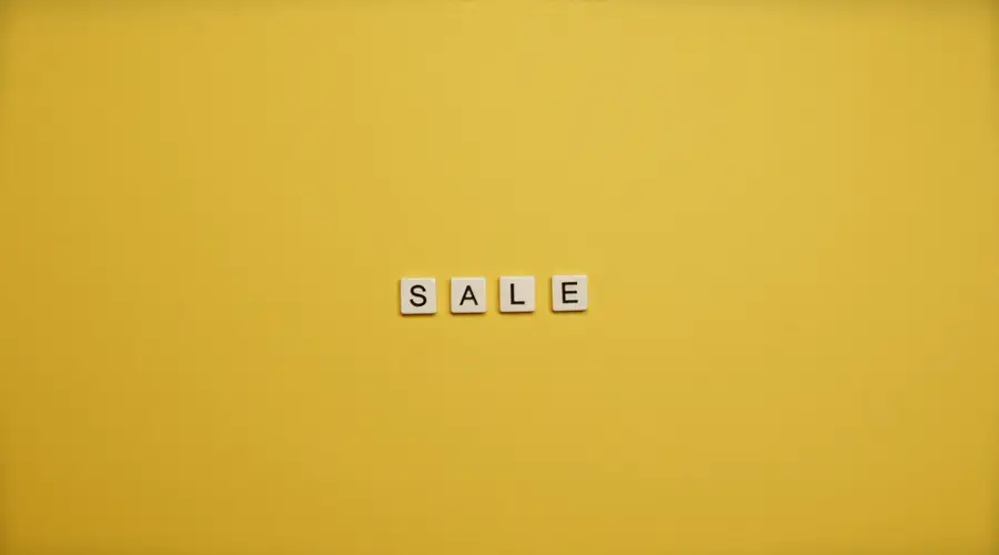 Single word 'SALE' spelled with tiles on a bright yellow background, ideal for advertising.