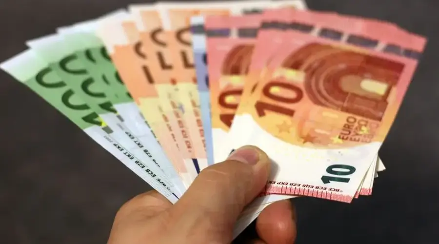 A fan of euro banknotes in various denominations held in a hand.