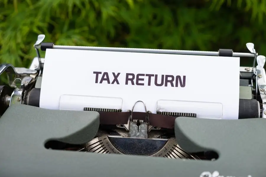 Close-up of a vintage typewriter typing 'Tax Return' on paper outdoors.