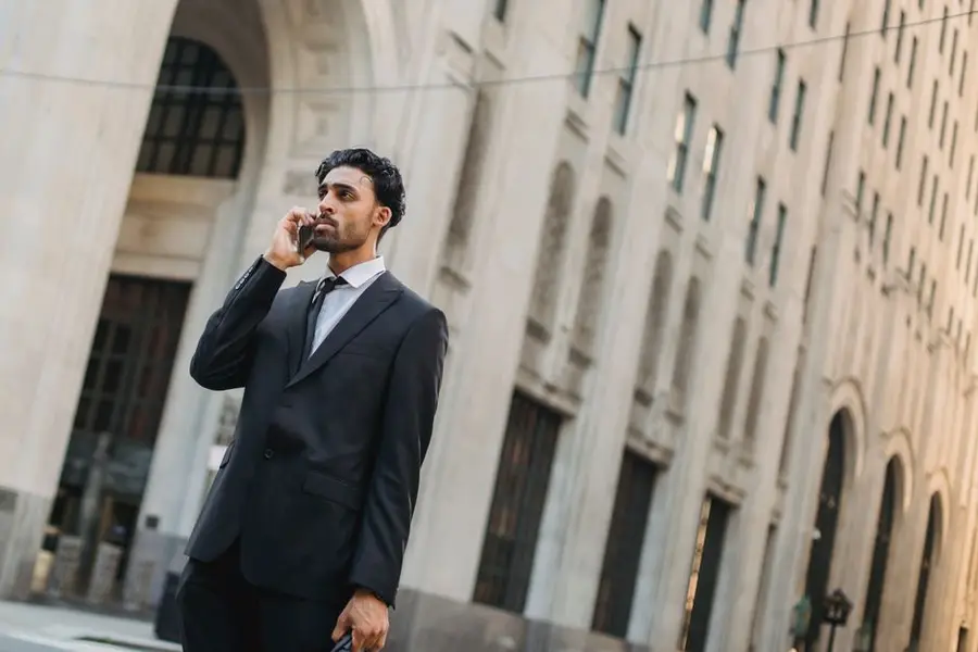 A professional man in a suit making a phone call on a city street, capturing urban business life.