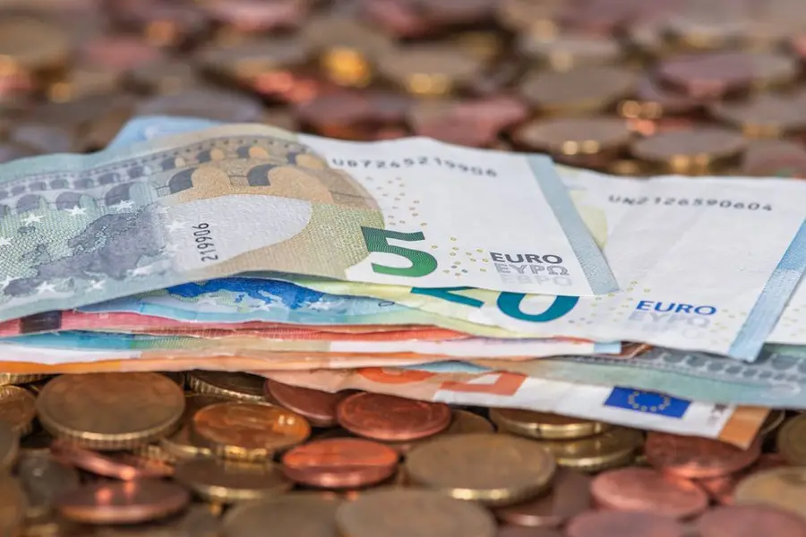 Stack of euro banknotes and scattered coins symbolizing wealth and finance.