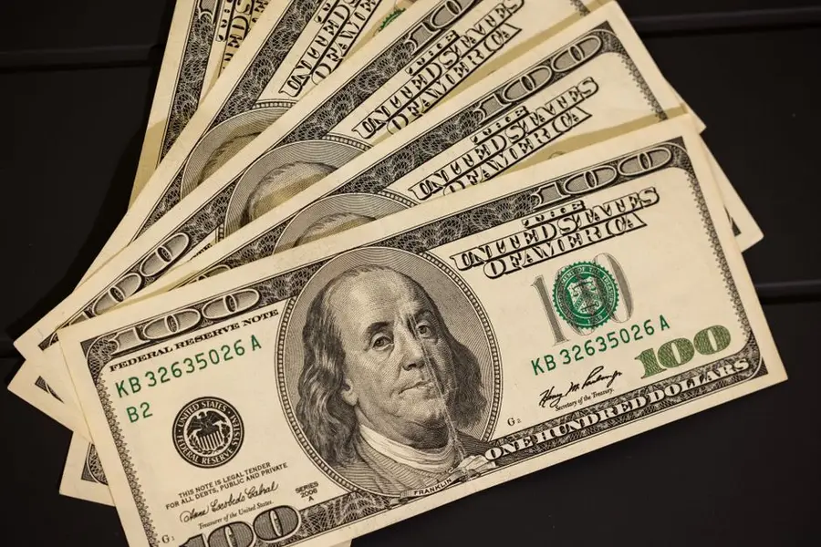 Close-up of US hundred dollar bills fanned out on a black surface for financial themes