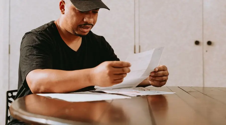 Adult man sitting at home table, focused on reviewing important documents.