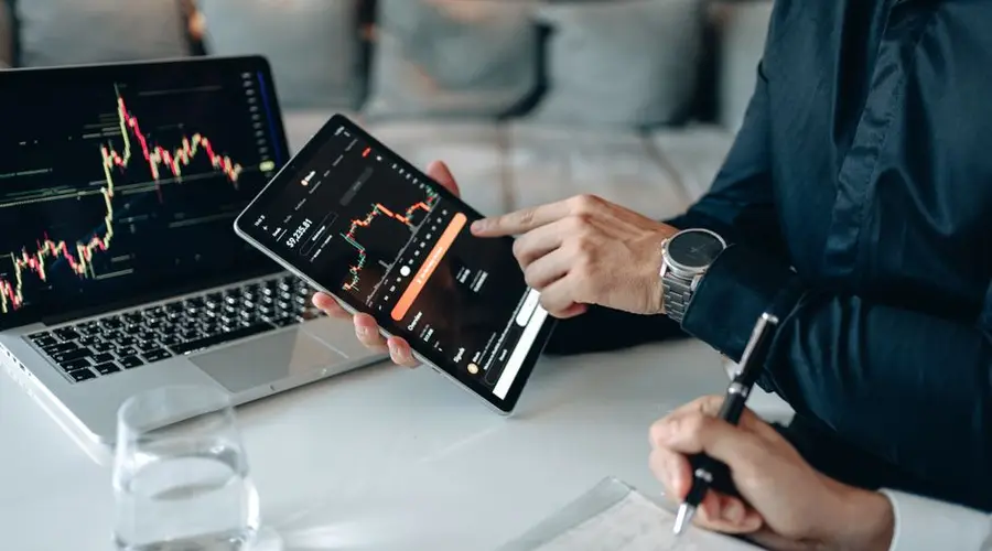 Two professionals analyzing stock graphs on digital devices in a modern business setting.