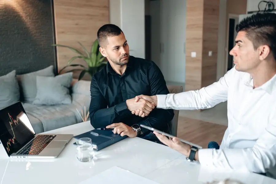 Two businessmen shaking hands in a modern office environment, sealing a deal.