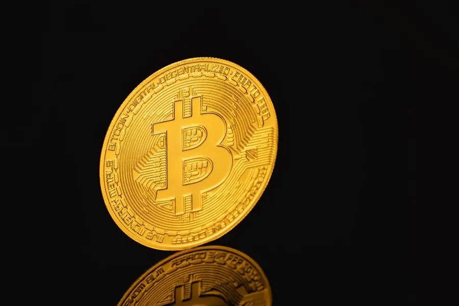 Elegant close-up of a Bitcoin coin reflecting on a black surface, symbolizing digital currency.