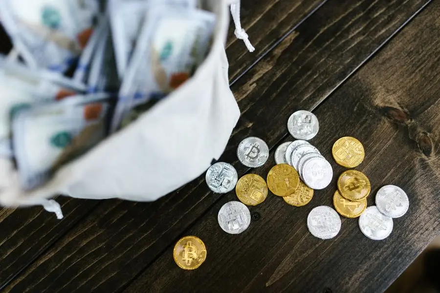 Close-up of scattered gold and silver cryptocurrency coins on a wooden surface.