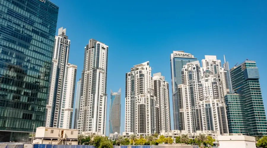 Modern skyscrapers stand tall against a clear blue sky in a vibrant cityscape, showcasing urban architecture.