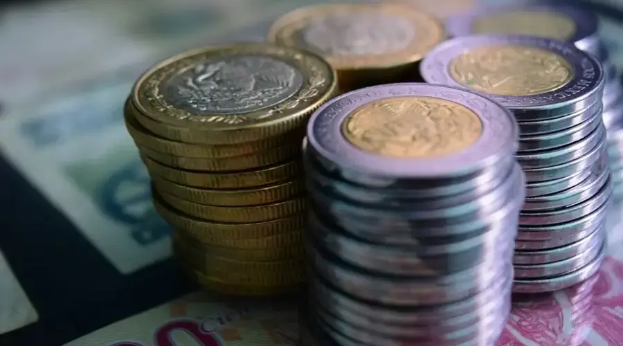 Close-up of stacked gold and silver coins on various currency notes, symbolizing wealth and savings.