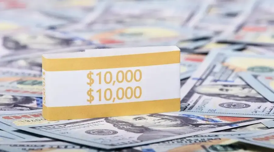 Close-up image of a stack of US dollars with a $10,000 band, symbolizing wealth and finance.