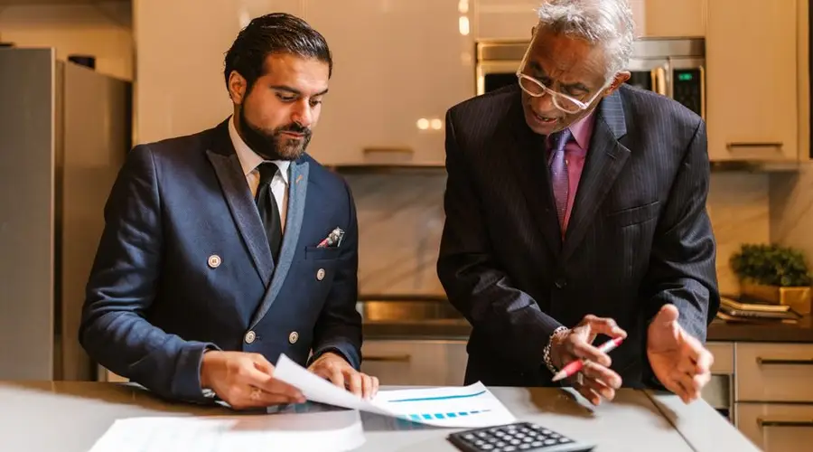 Two businessmen engaged in a focused discussion over financial documents in a modern office setting.