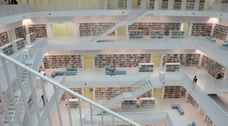 Contemporary library interior featuring white staircases and bookshelves, showcasing modern architecture.