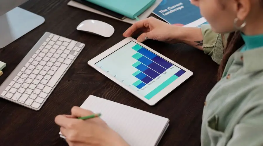 Woman reviewing digital graphs on tablet in an indoor workspace. Perfect for business and technology themes.