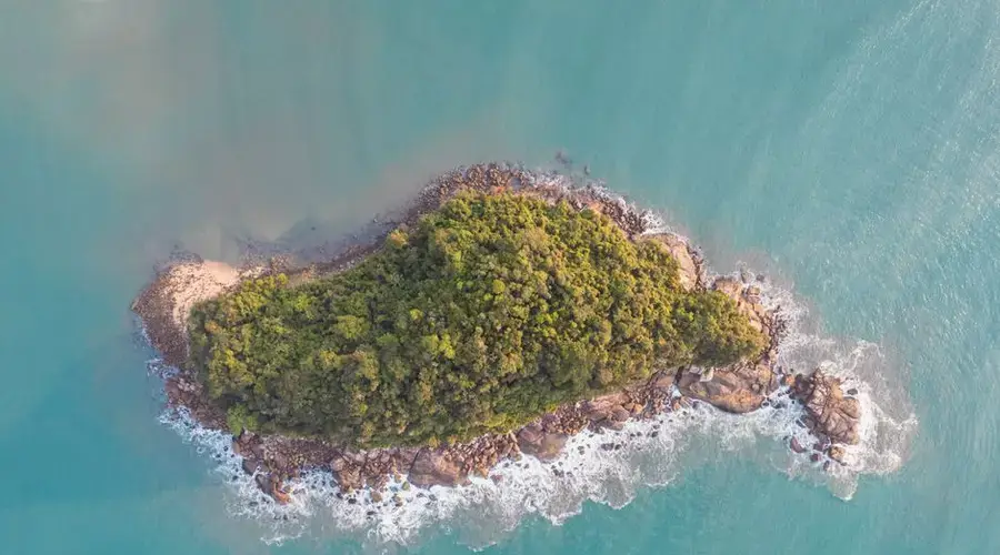 Stunning aerial photo of a lush green island surrounded by turquoise ocean waters in Ubatuba, Brazil.