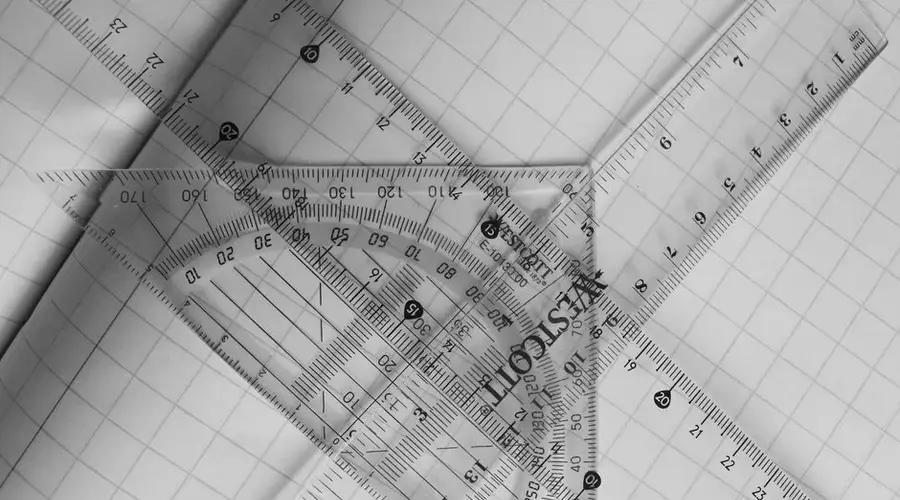 A black and white photo of geometric rulers arranged on graph paper, emphasizing precision and design.