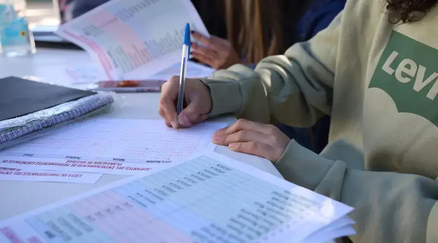 Person writing on documents outdoors, focusing on planning and organization.