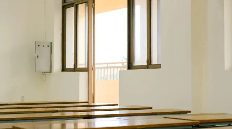 Sunlit classroom interior with open door and wooden desks, ideal for educational themes.