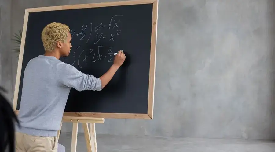 Back view of African American student with marker writing task on blackboard while studying in classroom