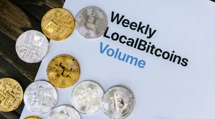 Image of Bitcoin tokens on a Weekly LocalBitcoins volume report paper.