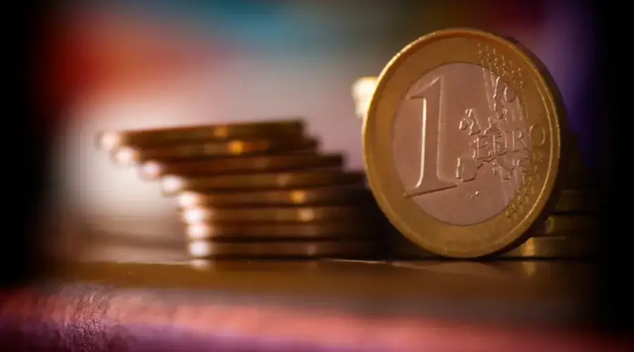 A close-up shot of stacked euro coins with a blurred colorful background, representing financial concepts.