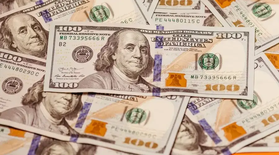 Close-up of multiple US hundred dollar bills featuring Benjamin Franklin, emphasizing wealth and finance.