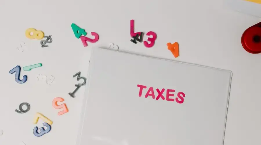 Colorful magnetic numbers scattered around a file labeled 'TAXES', symbolizing financial organization.