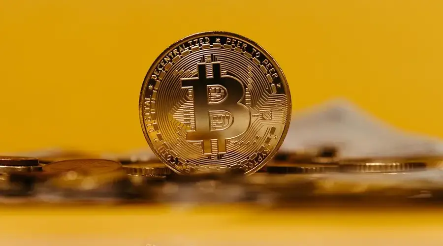 Close-up of a Bitcoin coin with a yellow background, representing cryptocurrency.