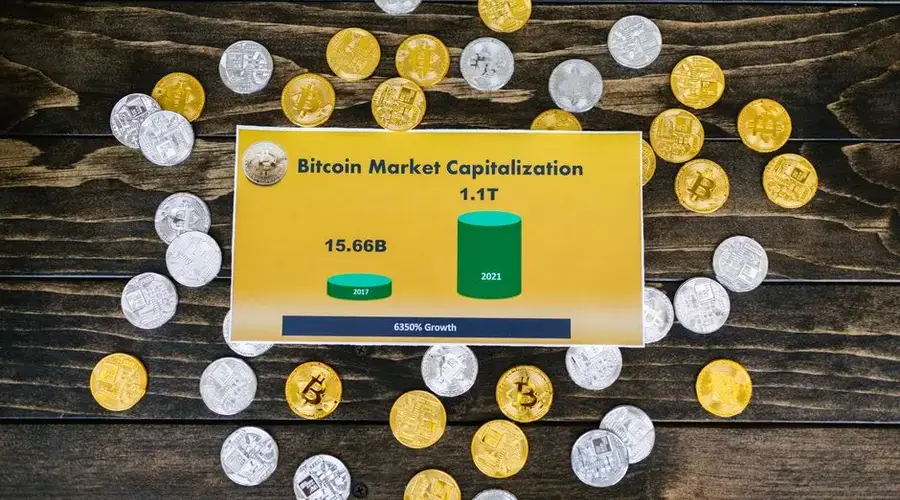 Bitcoin coins on wooden surface with chart showing market cap growth to 1.1T.