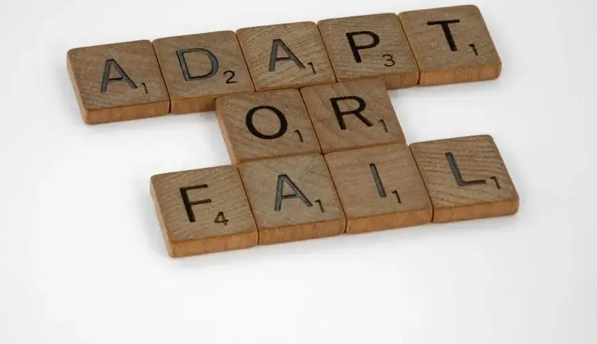 Scrabble tiles spell 'Adapt or Fail' on a white background, conveying a motivational message.