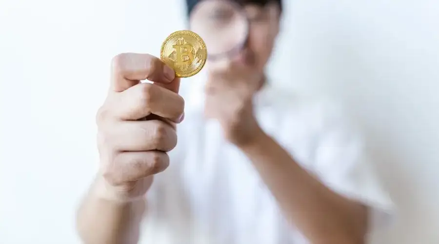 A person holds a bitcoin coin, highlighting its importance and value.