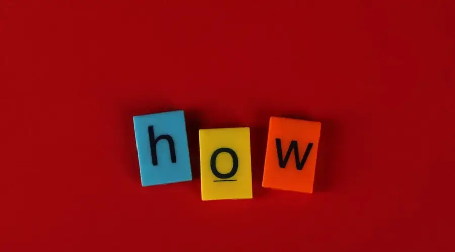 Colorful letter tiles spelling 'How' on a vibrant red background, ideal for educational content.