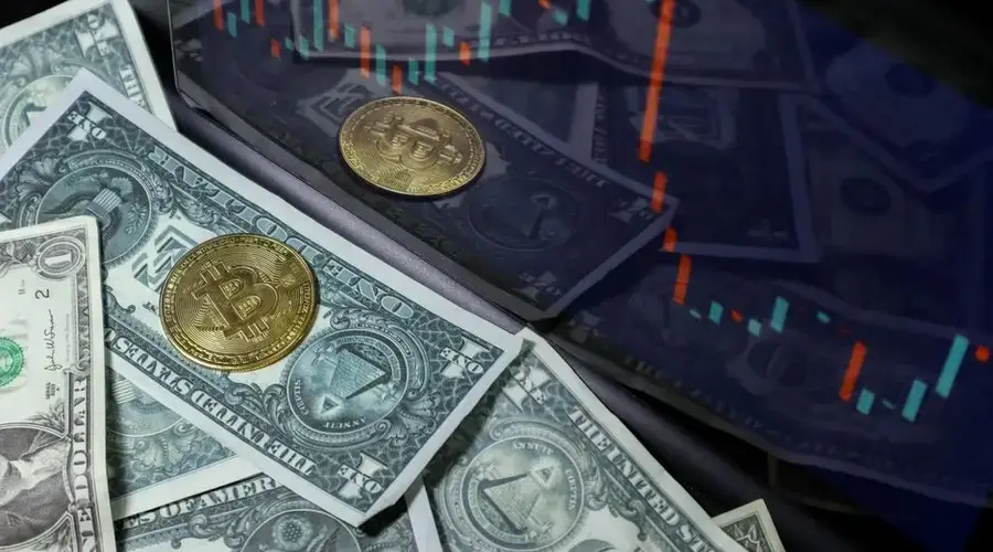 Bitcoin coin on US dollar bills with a stock market chart background. Represents cryptocurrency and finance.