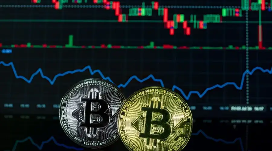 Close-up of Bitcoin coins against a crypto market chart background.
